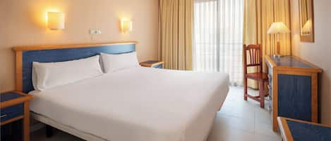 Una habitación de hotel con una cama grande, mesitas de noche, un escritorio y una silla.