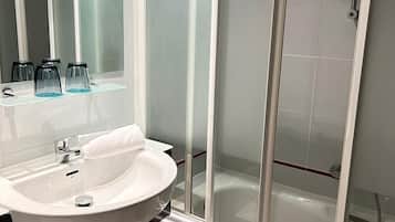 Une salle de bain moderne avec une douche à parois de verre, un lavabo blanc et un miroir.