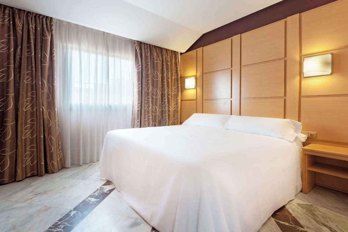 Habitació d'hotel amb un llit gran, parets de fusta i un paviment de marbre.