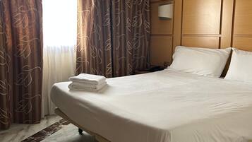 A hotel room with a large bed, wooden headboard, and a marble floor.