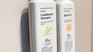 Dos botellas de champú y gel de baño sobre una pared blanca.
