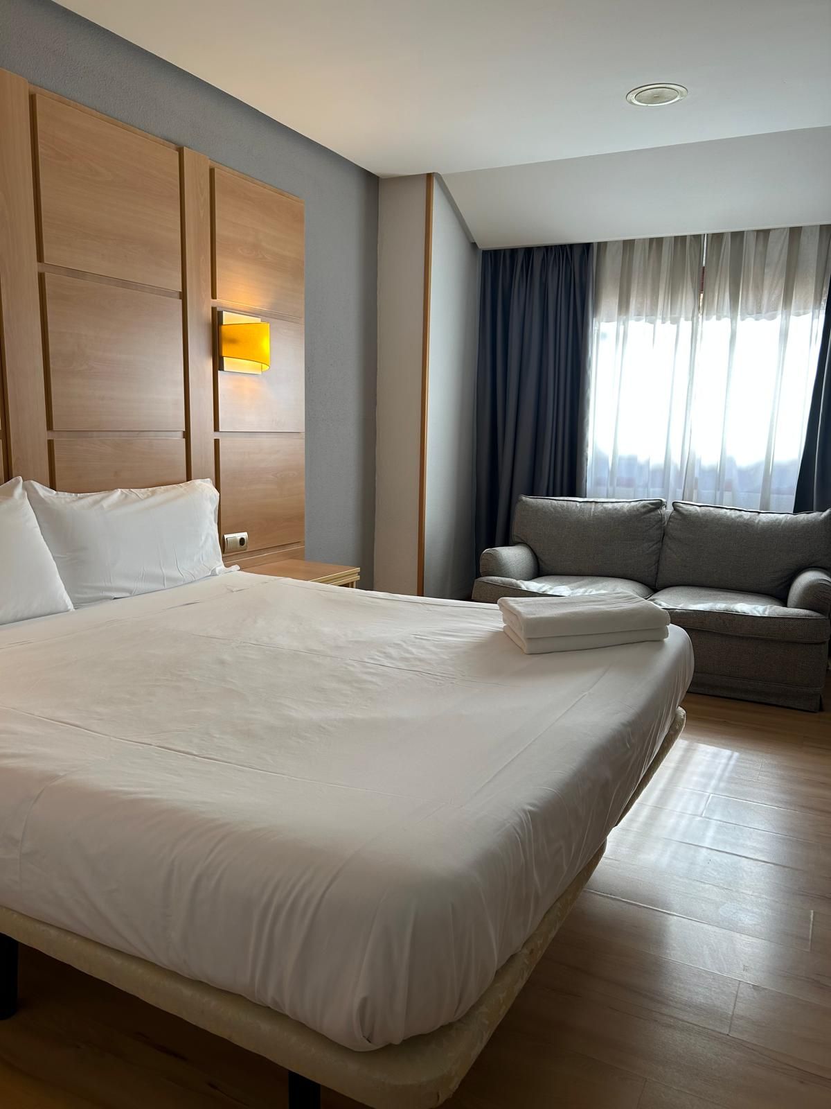 Ein Hotelzimmer mit einem großen Bett, einer Couch, einem Nachttisch und einer Lampe.