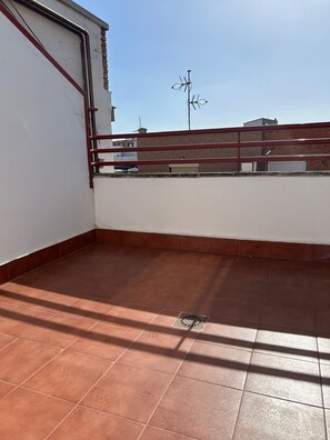 A rooftop terrace with a red metal railing, a clear sky, and a building in the background. - Hotel Puertollano 3* by eme hoteles (Puertollano)