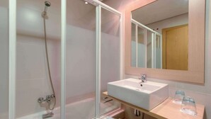 A modern bathroom with a glass-enclosed shower, a white sink, and a wooden vanity. - Hotel Puertollano 3* by eme hoteles (Puertollano)