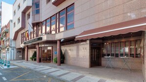A hotel with a modern facade, a prominent entrance, and a visible outdoor seating area. - Hotel Puertollano 3* by eme hoteles (Puertollano)