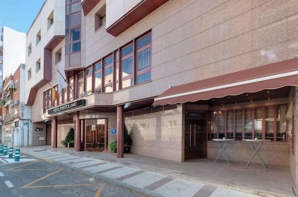 Un hotel con fachada moderna, una entrada destacada y un espacio al aire libre para sentarse.