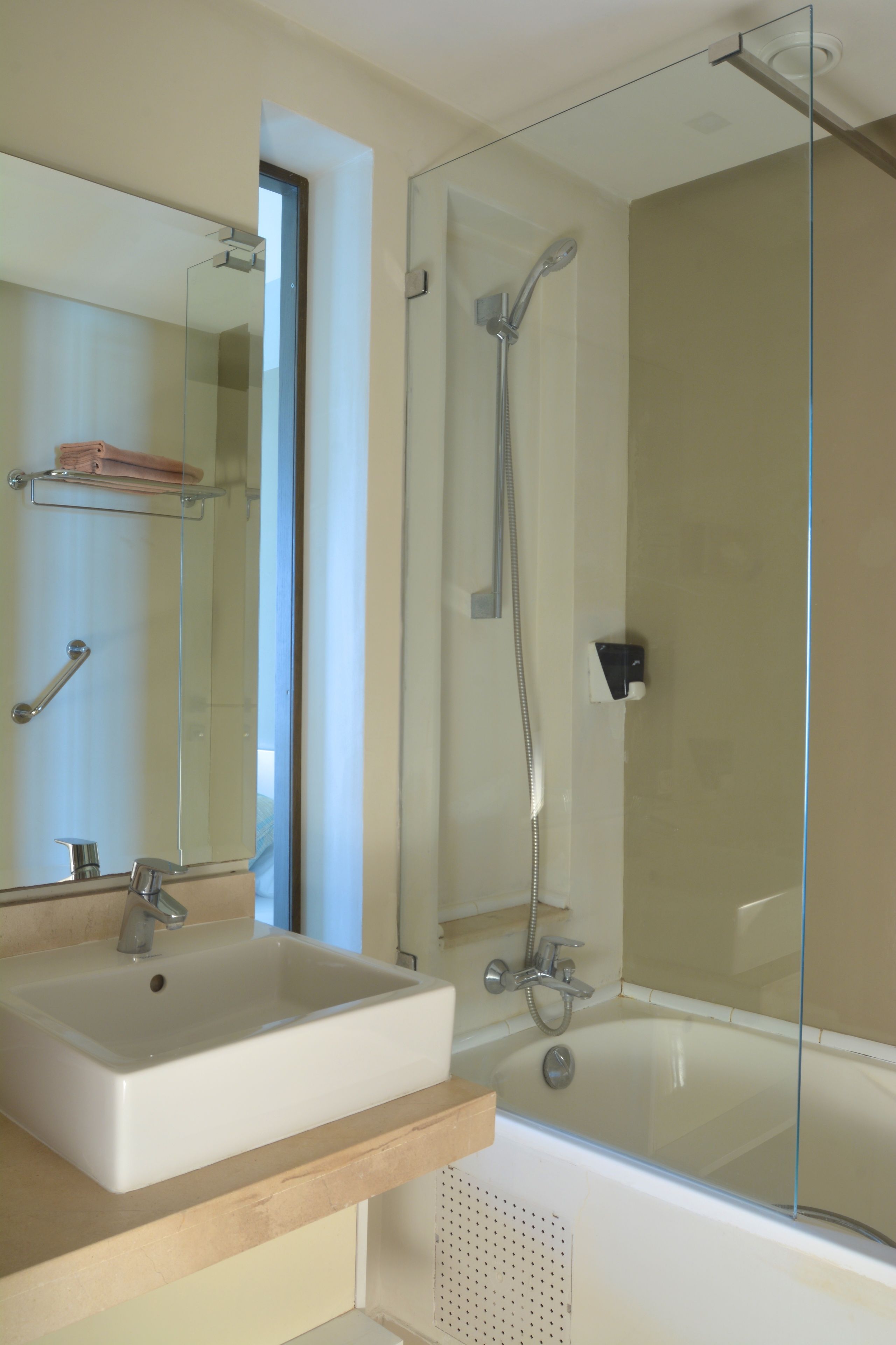 A bathroom with a glass-enclosed shower, a sink, and a mirror.