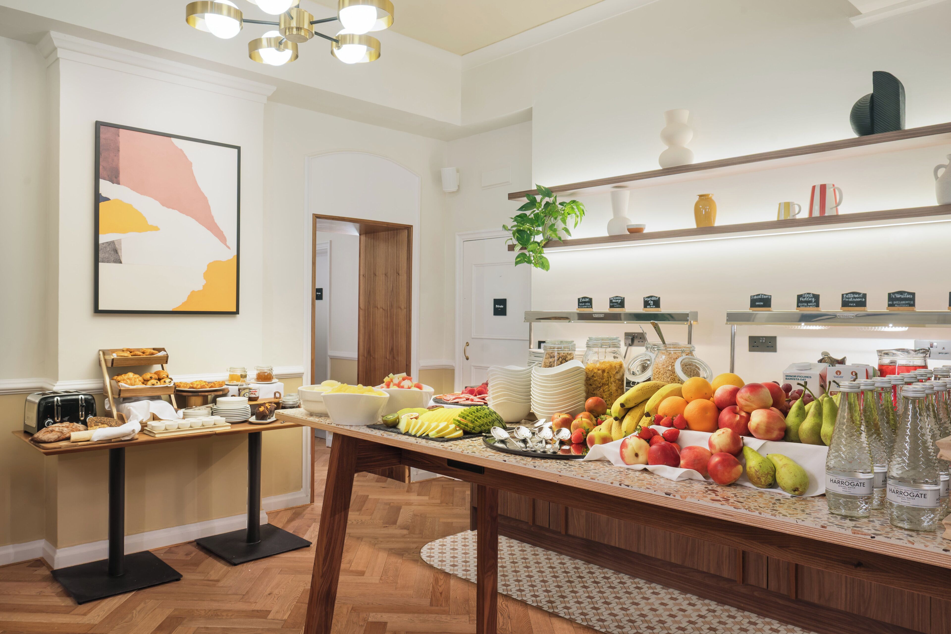 A breakfast buffet with various fruits, pastries, and beverages.