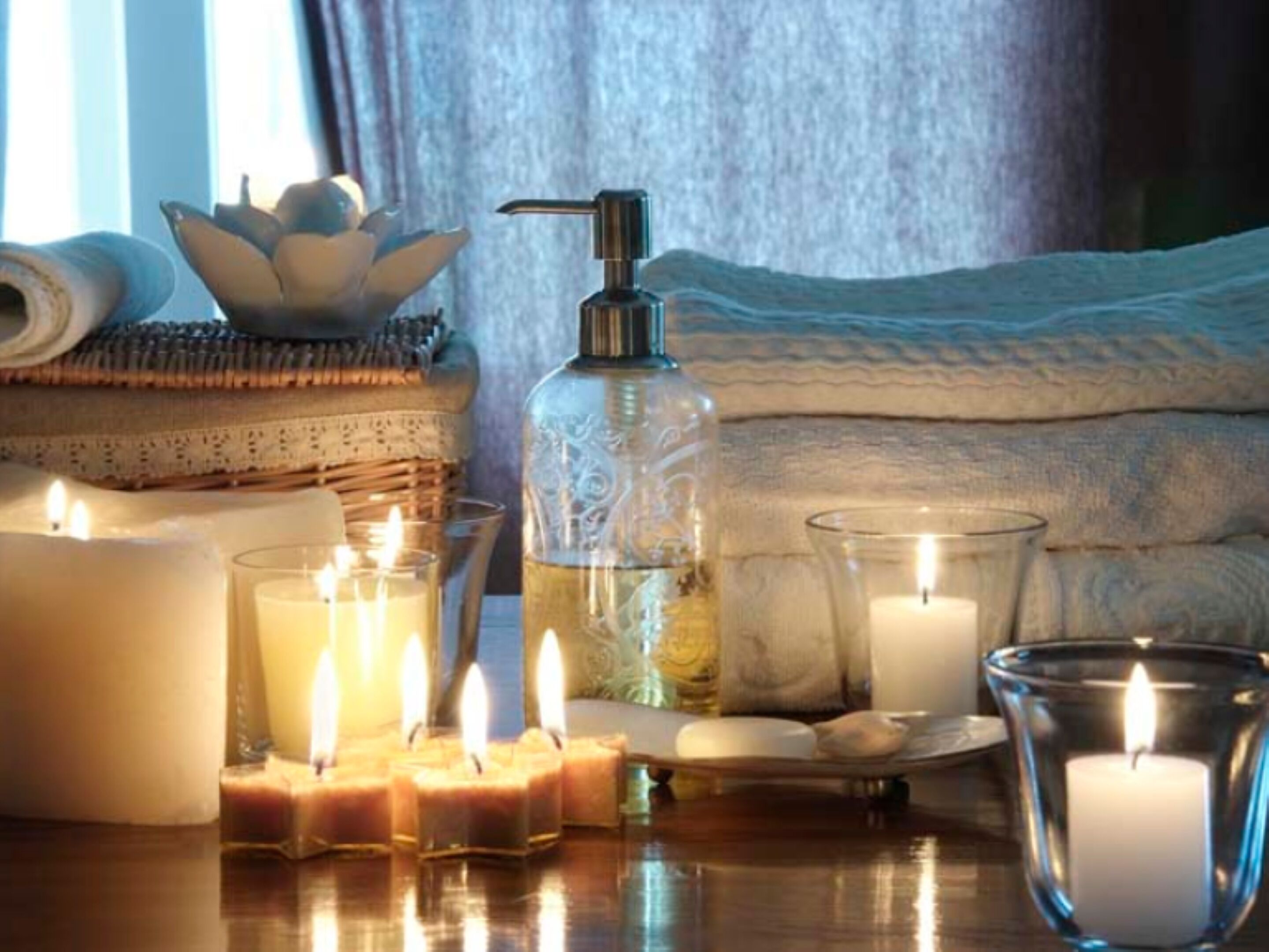 A cozy bedroom with a bed, candles, and a bottle of lotion.