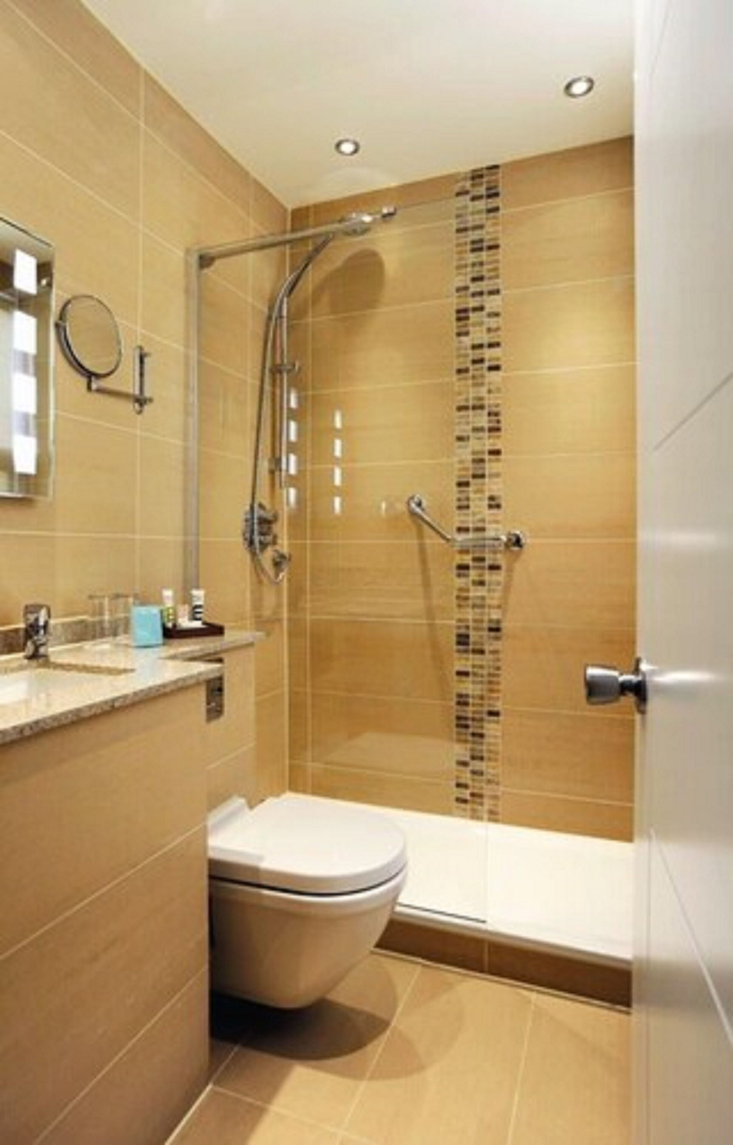 A modern bathroom with a glass-enclosed shower, a toilet, and a sink with a mirror above it.