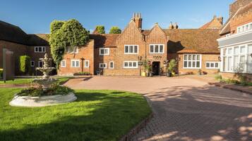 A traditional brick building with a central courtyard, a fountain, and a well-maintained lawn.