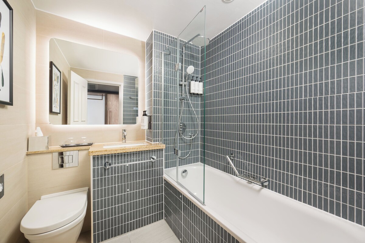 A modern bathroom with a bathtub, shower, and toilet.