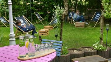 A garden with a pink table, blue chairs, and a wooden bench.