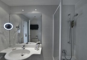 Ein modernes Badezimmer mit Waschbecken, Spiegel und Dusche.