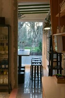 Una cocina con puerta de cristal que da a un patio, una mesa con sillas y estantes con botellas.