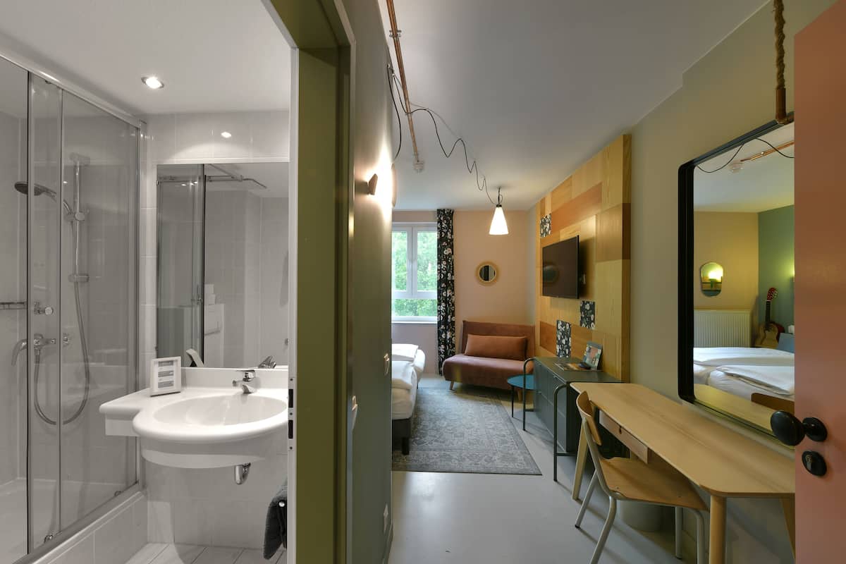A modern bathroom with a glass shower enclosure, a sink, and a vanity with a mirror.