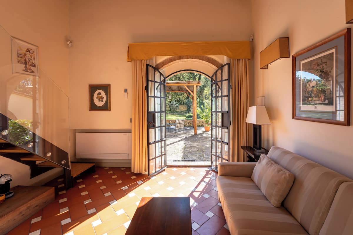 Una habitació amb un sofà, una taula i una escala que condueix a un balcó.