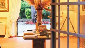 Eine Lobby mit einem Marmor-Rezeptionsschalter, einer Vase mit Pampasgras und Blick auf den Garten durch ein großes Fenster.