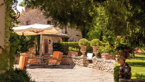 Eine Terrasse im Freien mit Steinboden, einem Tisch mit Stühlen und Blumentöpfen.