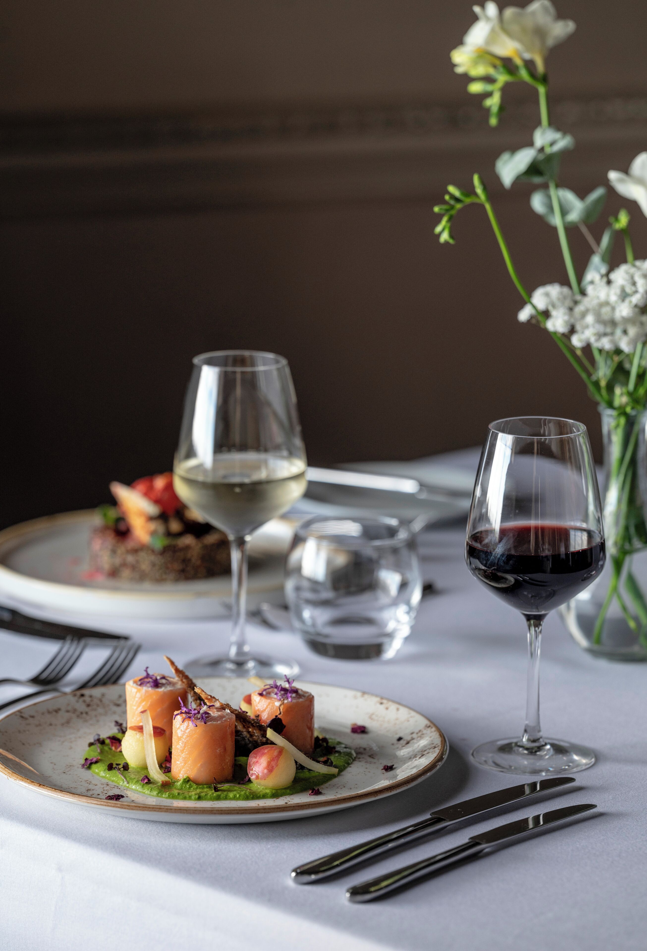 Une table à manger avec des assiettes remplies de nourriture, des verres à vin et des couverts.