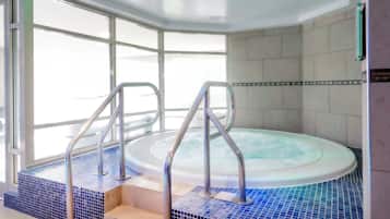 A hot tub with metal railings, tiled steps, and a view through large windows.