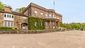 A historic building with a stone facade, a covered porch, and a gravel driveway. - Wood Hall Hotel and Spa (Wetherby)
