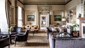 A classic, elegantly furnished living room with a patterned carpet, leather sofas, and a fireplace. - Wood Hall Hotel and Spa (Wetherby)