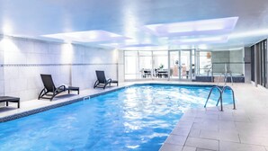 An indoor swimming pool with two lounge chairs, a hot tub, and a glass-enclosed dining area. - Wood Hall Hotel and Spa (Wetherby)