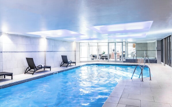 An indoor swimming pool with two lounge chairs, a hot tub, and a glass-enclosed dining area. - Wood Hall Hotel and Spa (Wetherby)