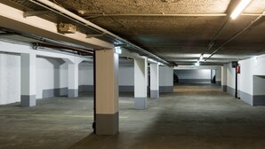 Un amplio estacionamiento subterráneo con pilares de hormigón y líneas amarillas delimitando los espacios.