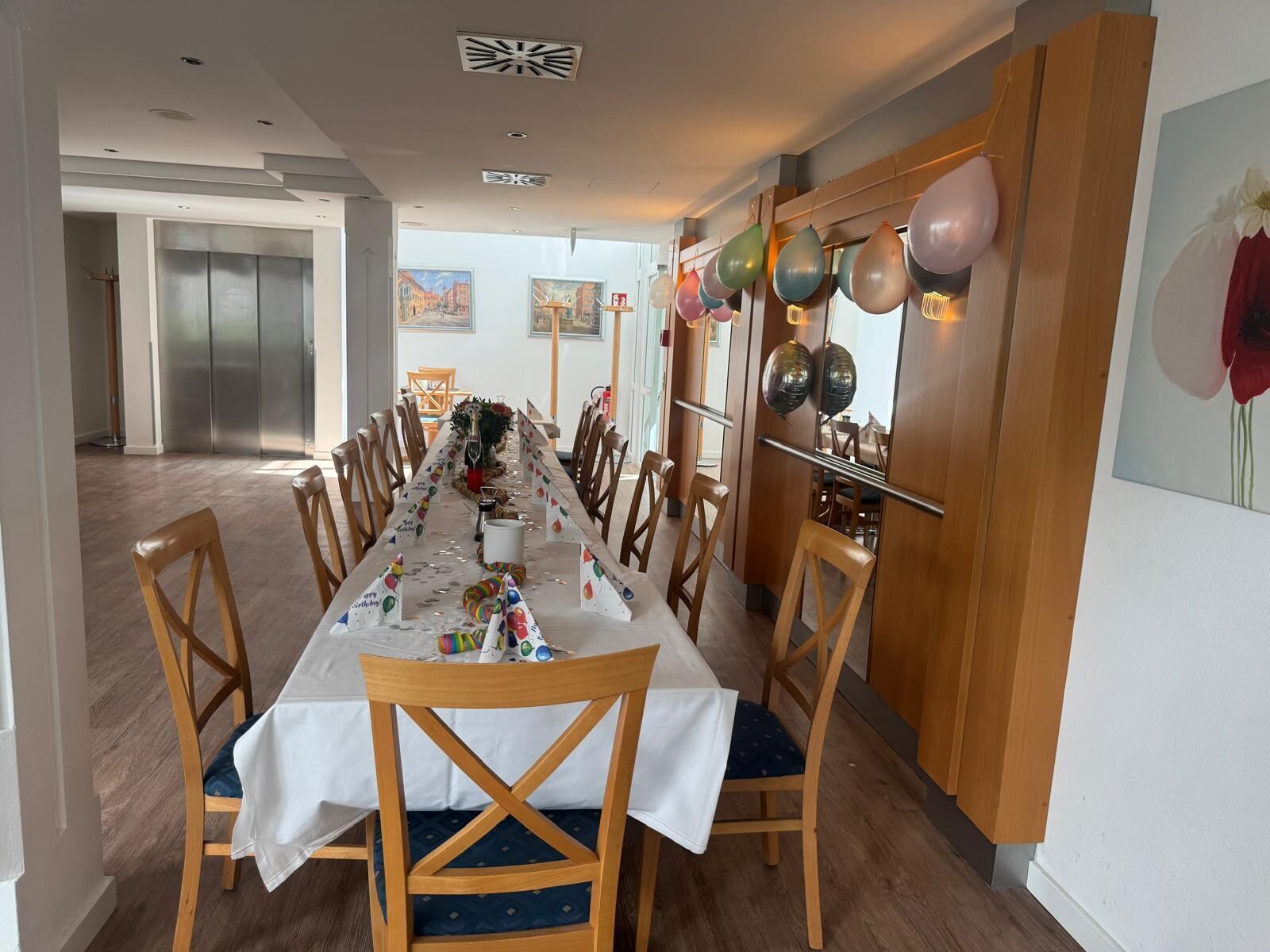 Una larga mesa de comedor con sillas, globos y un centro de mesa con un árbol de Navidad.