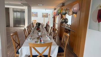 Una larga mesa de comedor con sillas, globos y un centro de mesa con un árbol de Navidad.