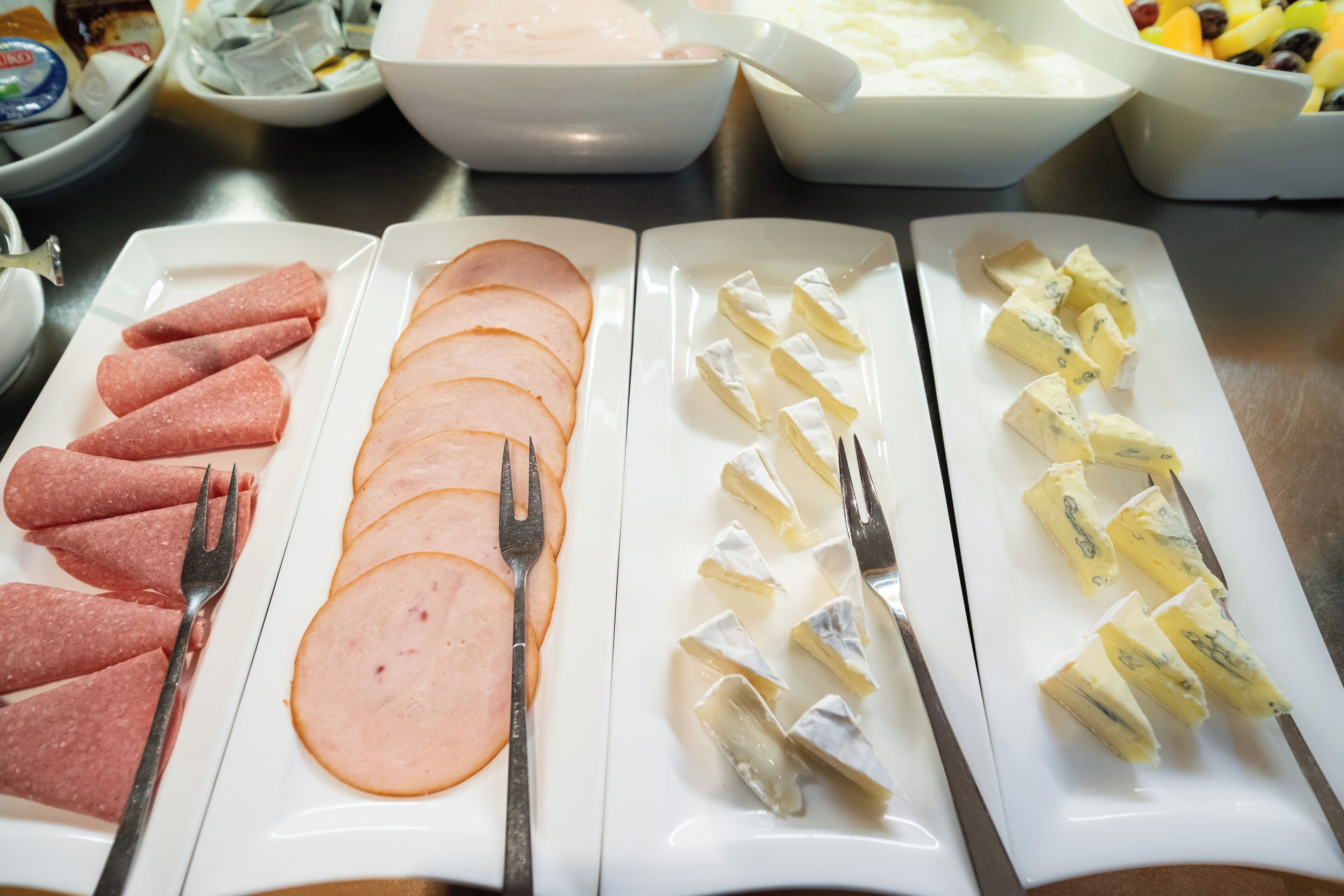 Ein Buffet mit verschiedenen Speisen, darunter Wurstaufschnitt, Käse und andere Feinkostprodukte.