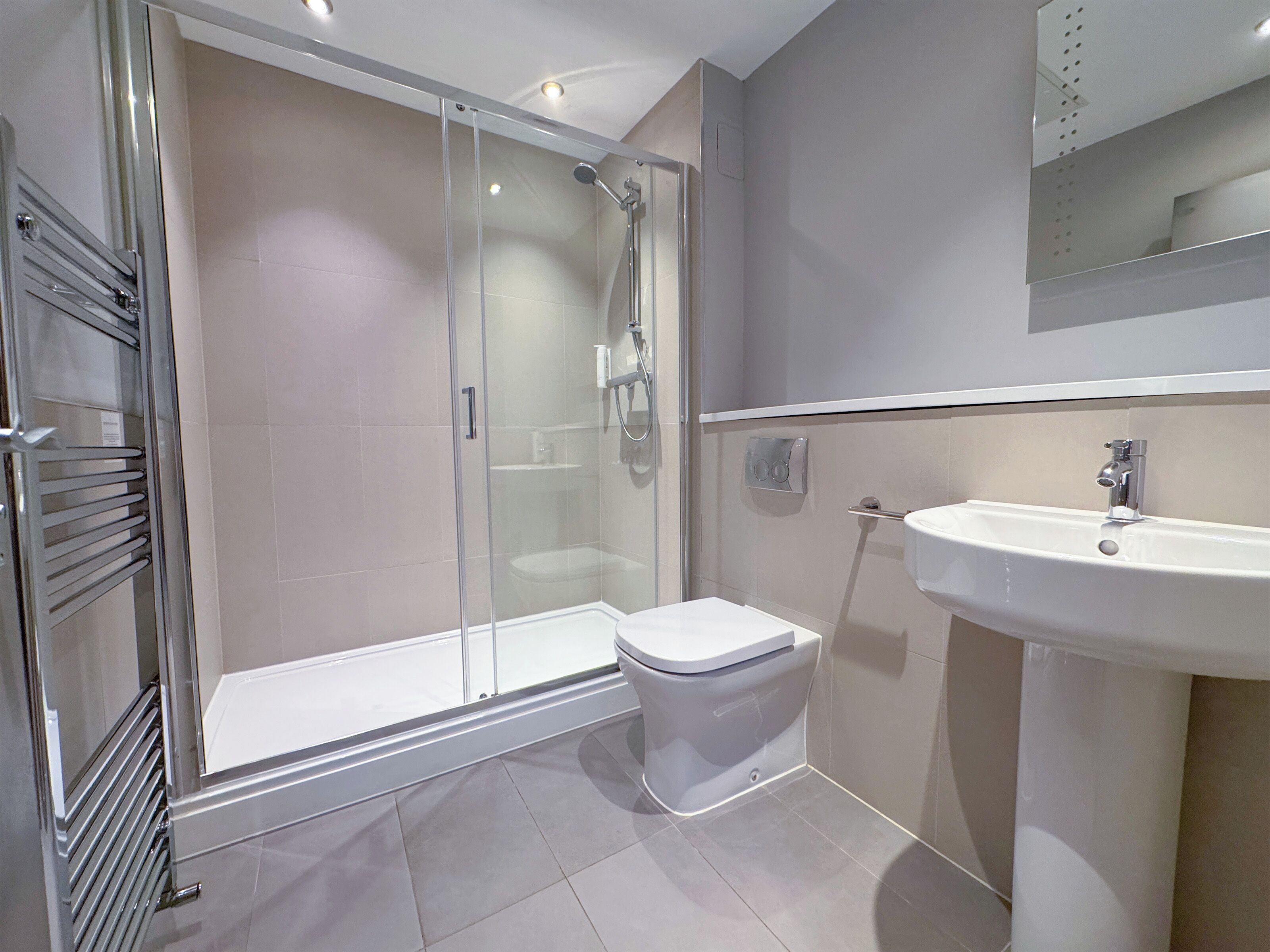 Un bagno moderno con doccia vetrata, un water bianco e un lavandino con specchio sopra.