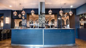 A bar area with a blue counter, hanging spherical light fixtures, and a central pillar.