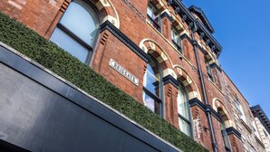 Un edificio de ladrillo rojo con ventanas arqueadas y un cartel que dice "Briggate".