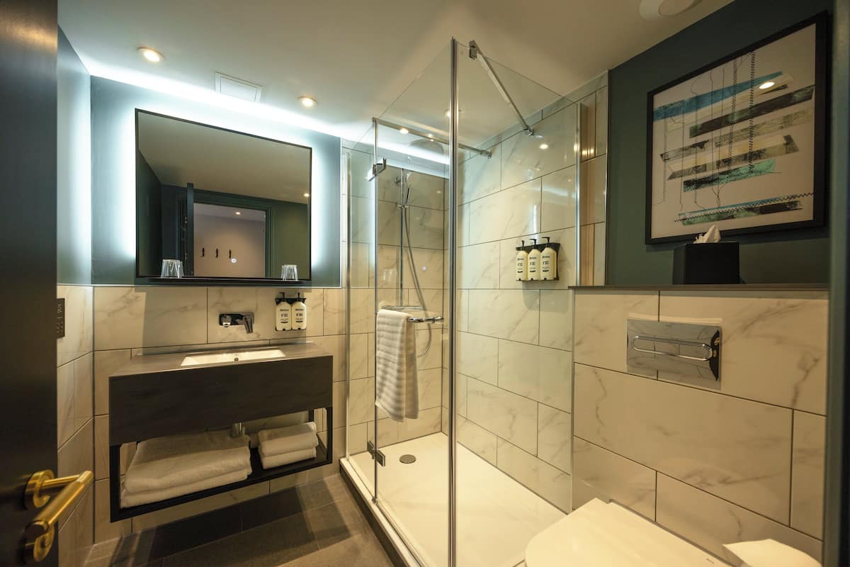 Un ba ño moderno con ducha de vidrio, tocador con espejo y un inodoro.