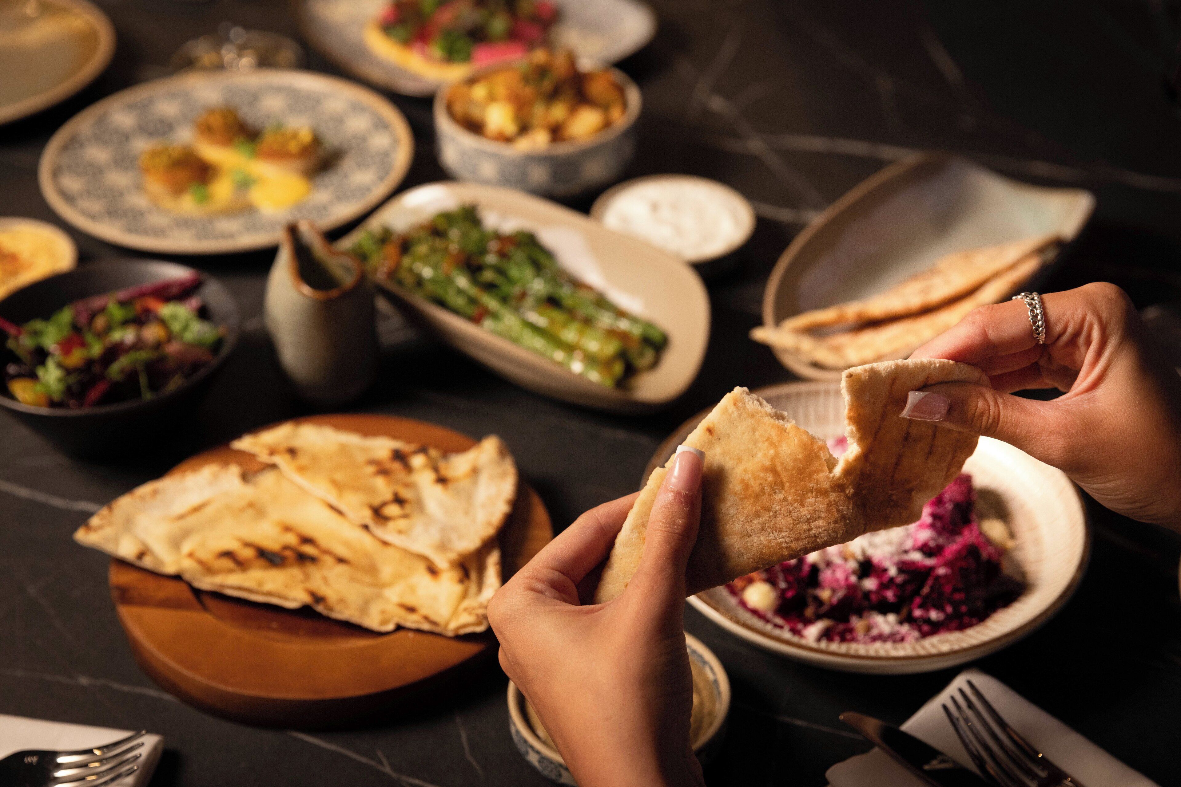 A dining table with various dishes, including flatbreads and a bowl of salad.
