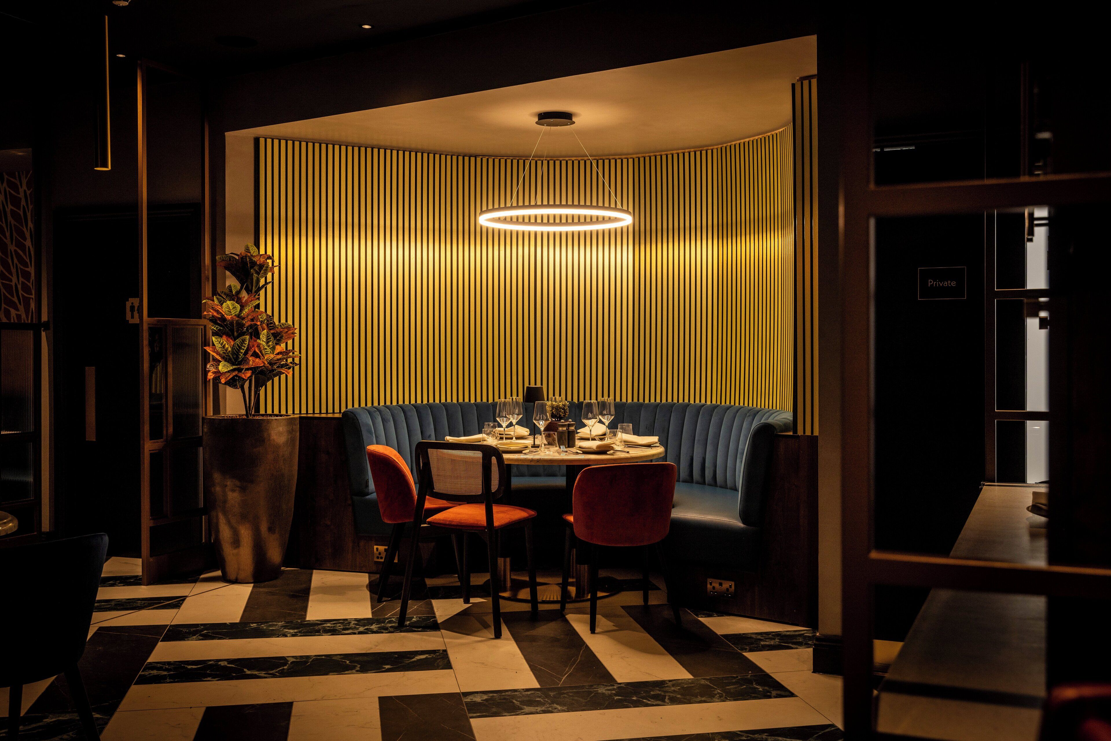 Ein Restaurant mit Schachbrettfußboden, einem runden Tisch und blauen Sitzbänken.
