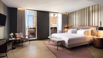 Una habitación de hotel con una cama grande, un escritorio, una silla, un televisor y vistas a la ciudad.