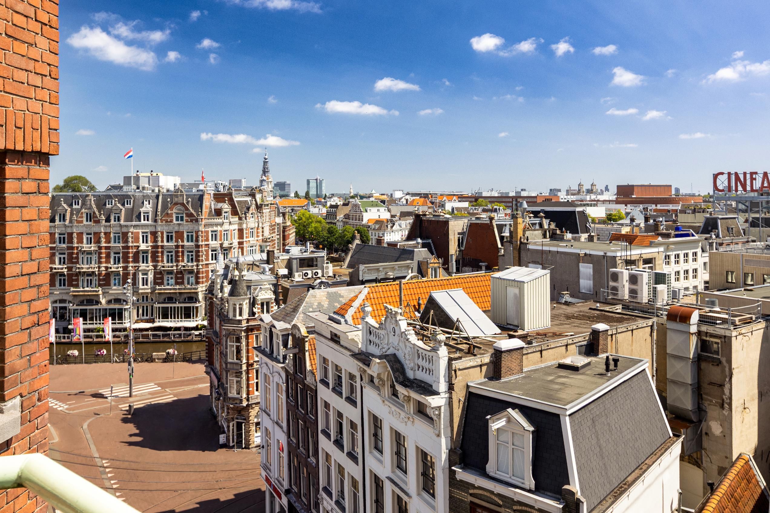 Un paisaje urbano con edificios históricos, cielo despejado y un cartel de cine.