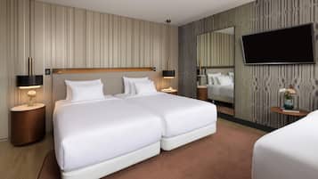 Habitació d'hotel amb un llit gran, dues taules de nit, un televisor de pantalla plana i un mirall a la paret.