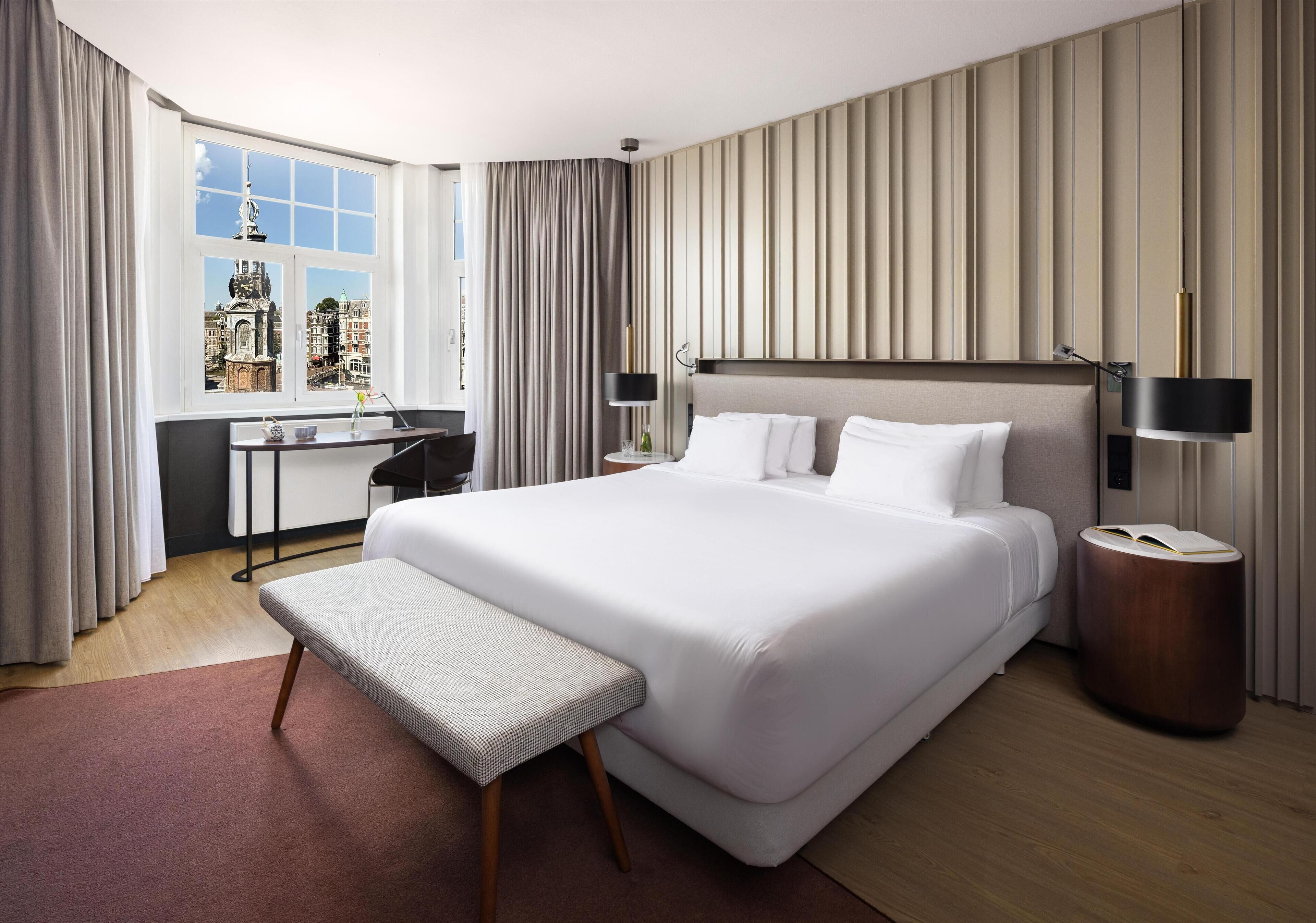 Una habitación de hotel con una cama grande, un escritorio y vistas a la ciudad.