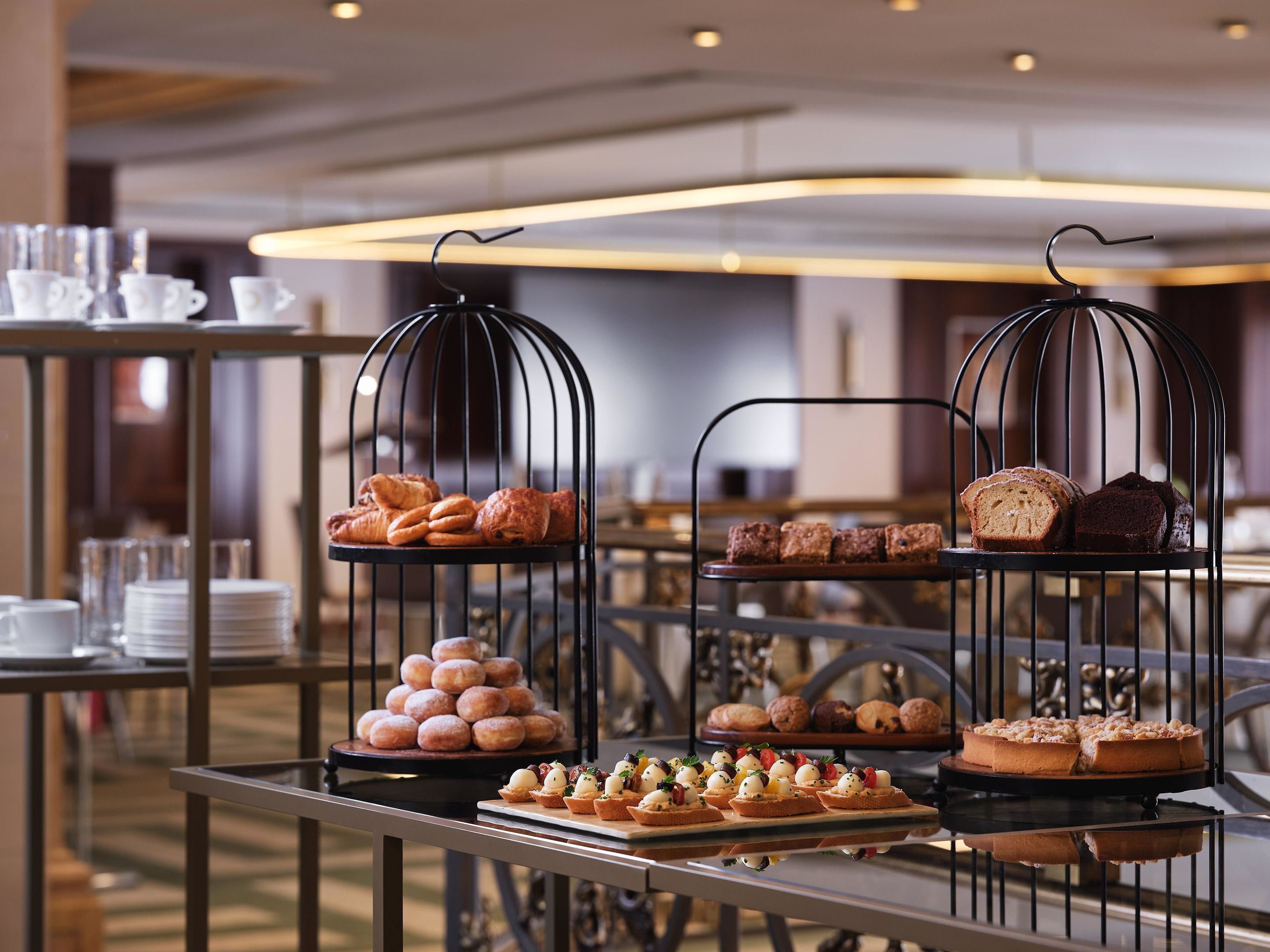 A buffet with various pastries and desserts displayed on metal stands.