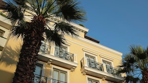 Un edificio de varios pisos con balcones, palmeras y un cielo azul despejado.