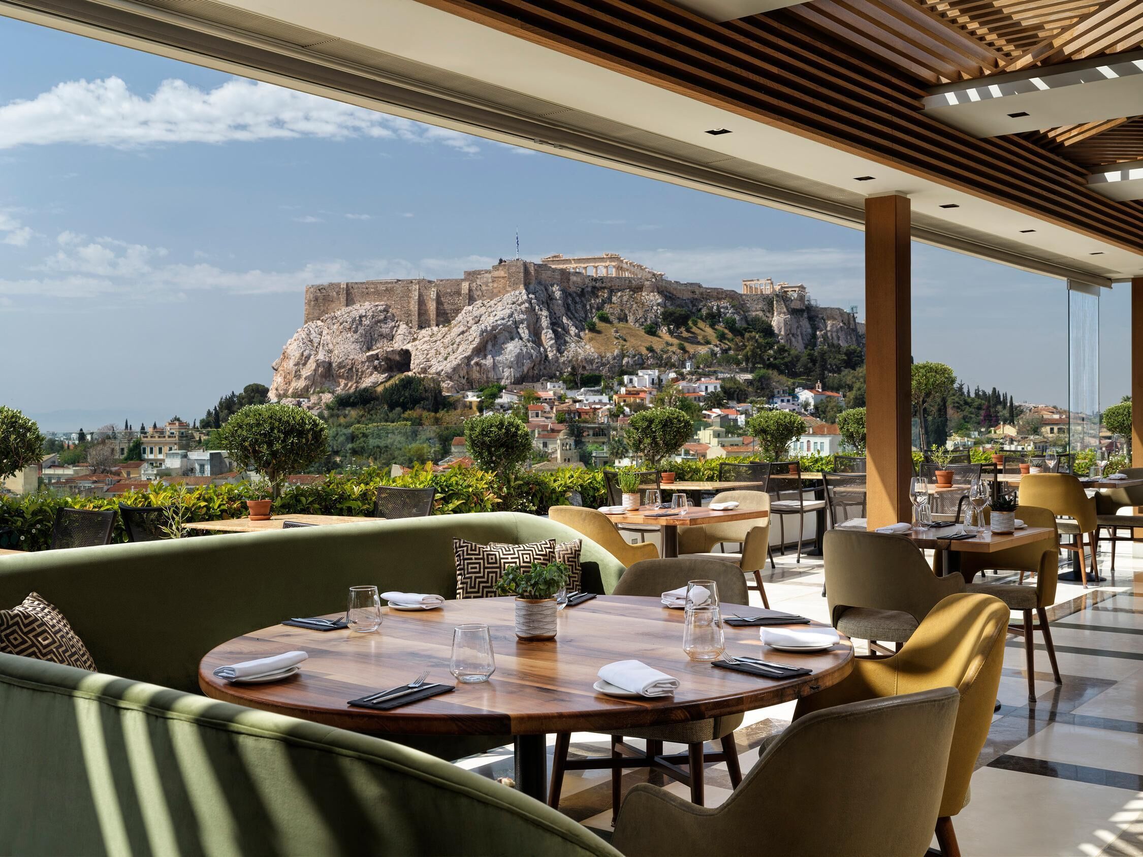 A restaurant with outdoor seating overlooking a historic fort. Tables are set with cutlery and glasses.