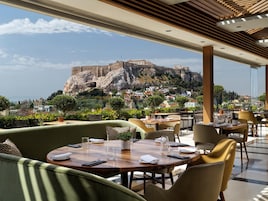 A restaurant with outdoor seating overlooking a historic fort. Tables are set with cutlery and glasses.
