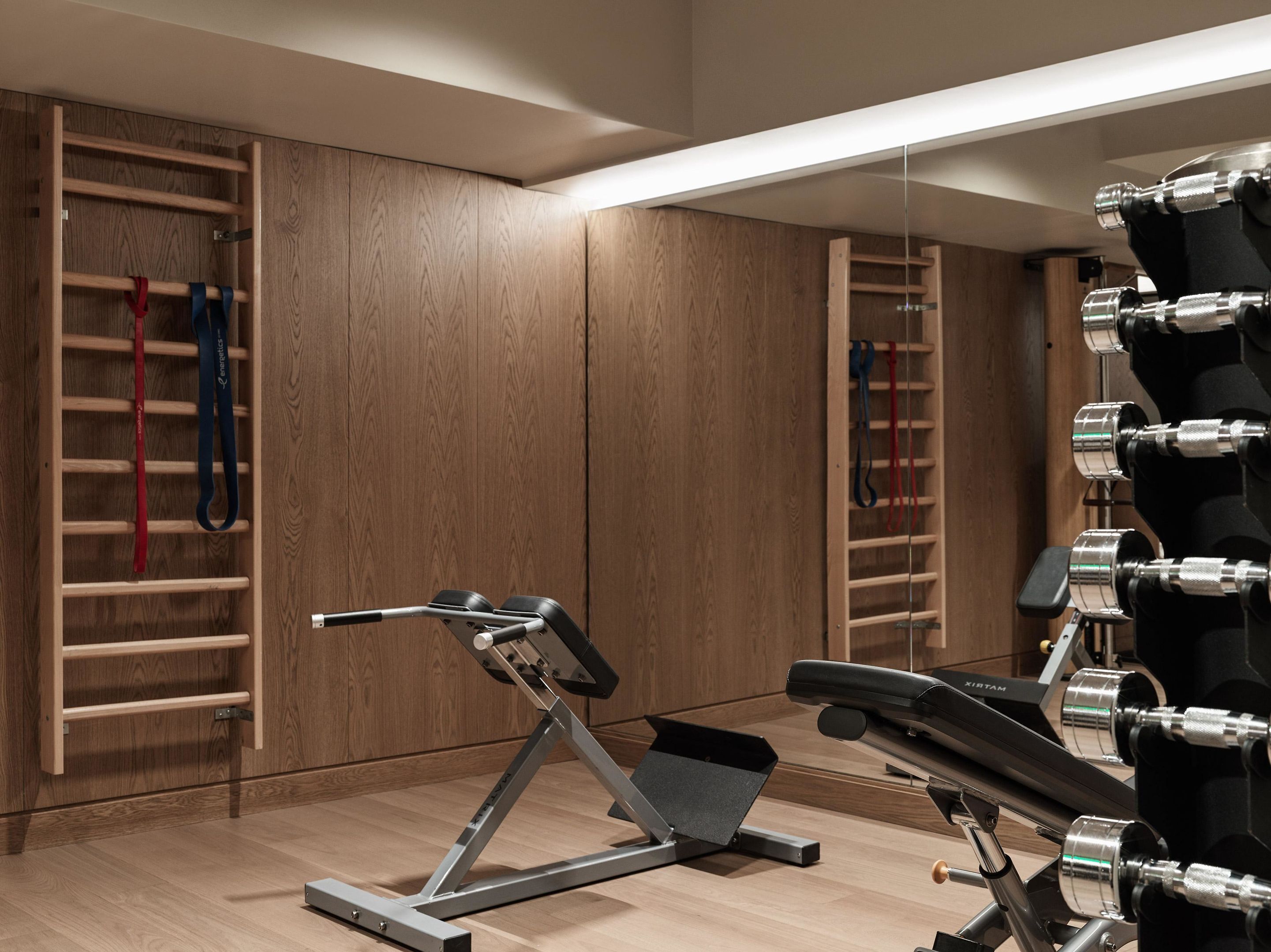 A modern gym with exercise equipment, wooden walls, and a ceiling light.