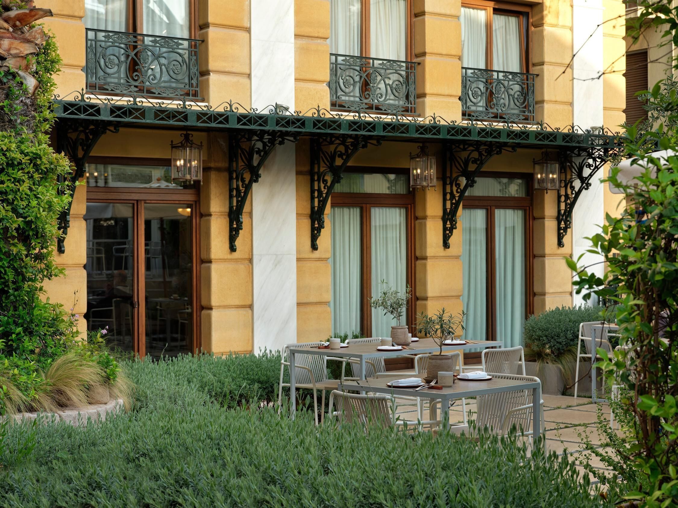 A building with a yellow facade, large windows, and a balcony with wrought iron railings.