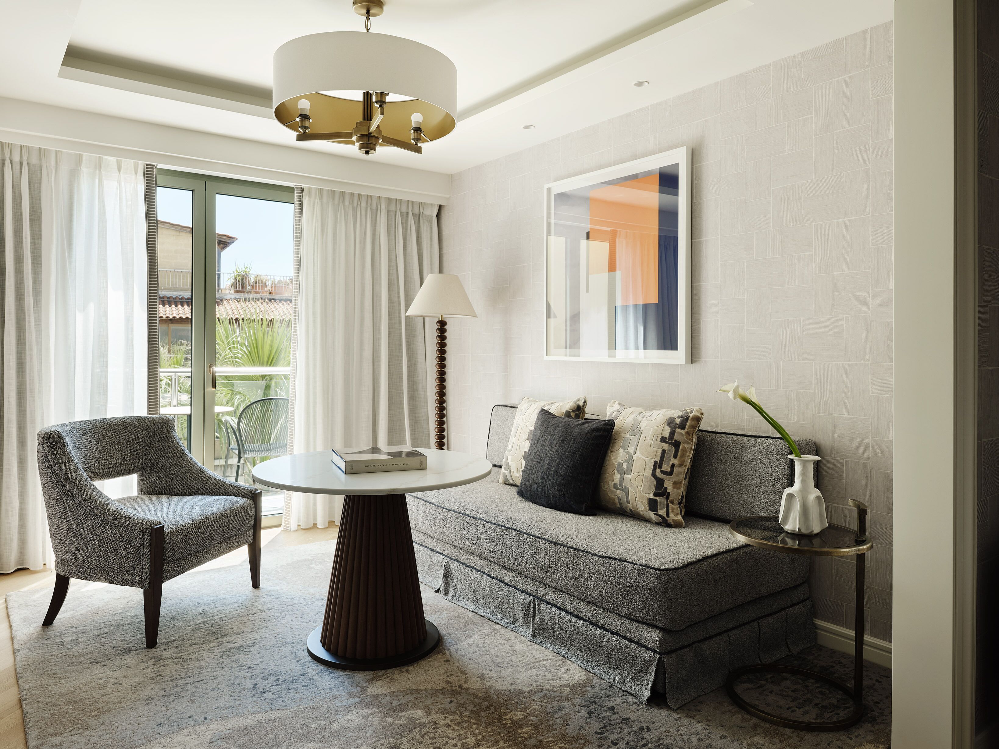 Een moderne woonkamer met een bank, fauteuil, rond tafel en een vloerlamp.